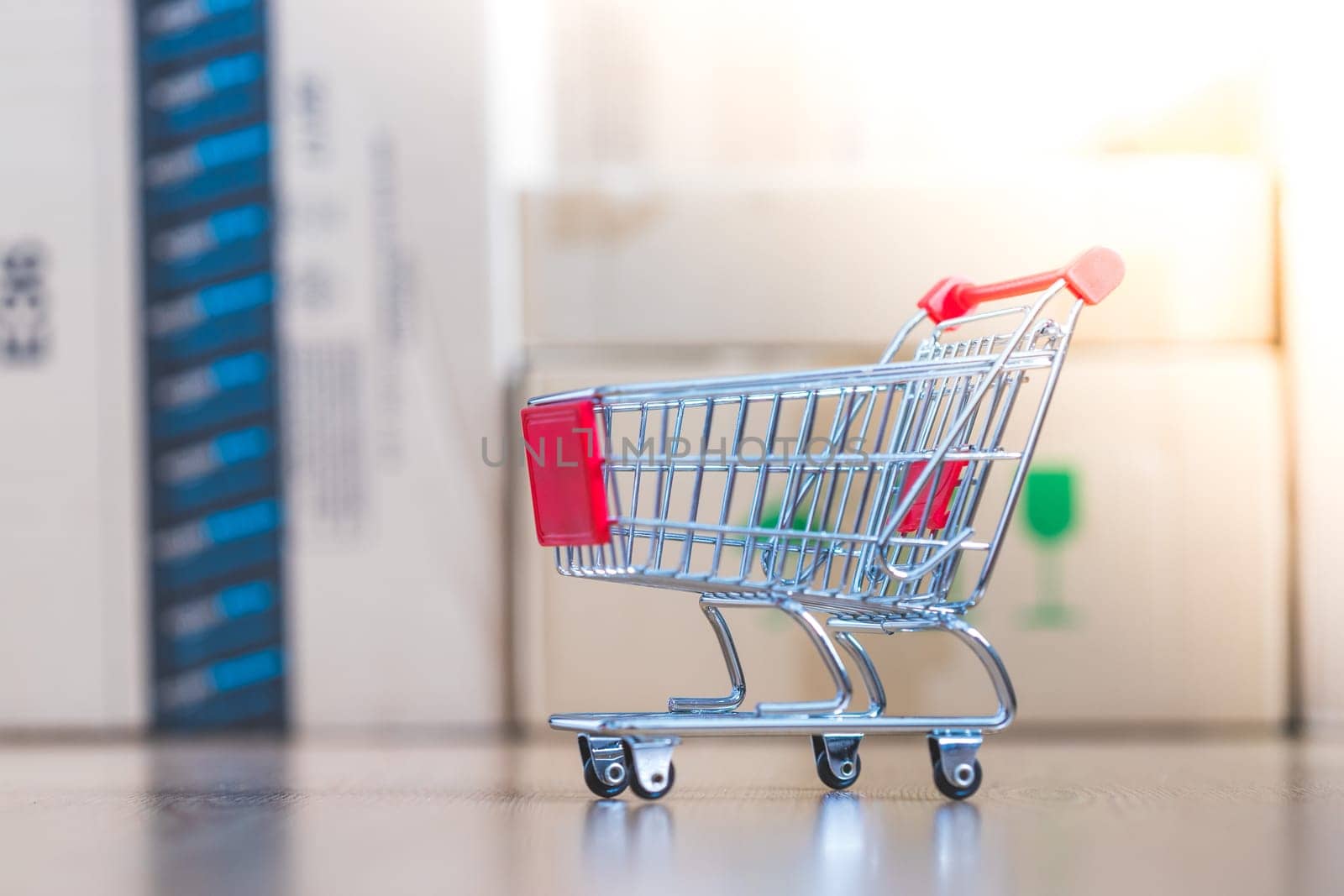 Online-Shopping and parcel service concept: Miniature shopping cart and cardboard boxes