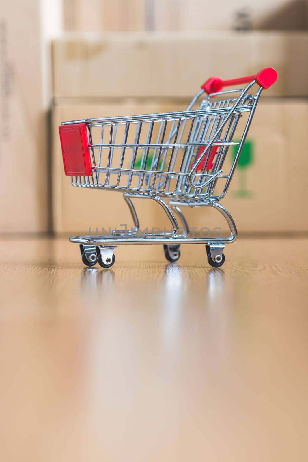 Online-Shopping and parcel service concept: Miniature shopping cart and cardboard boxes