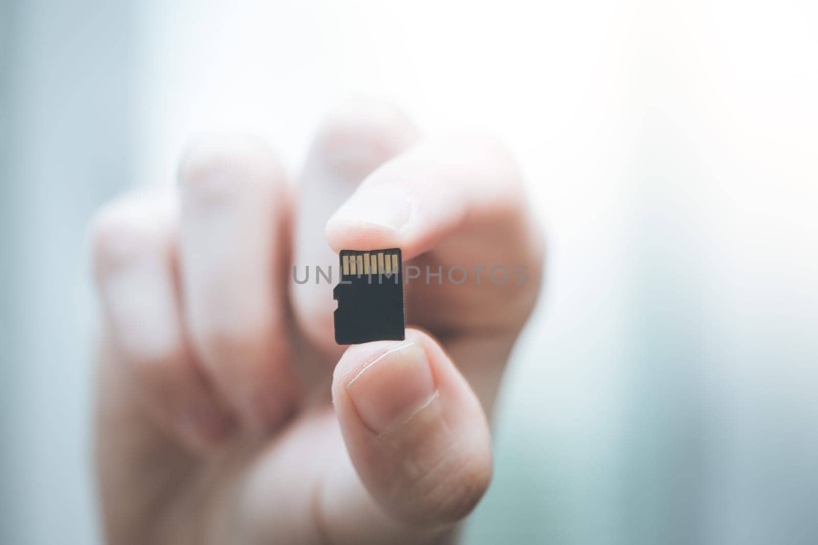 Young man is holding a tiny memory card in his hand, text space