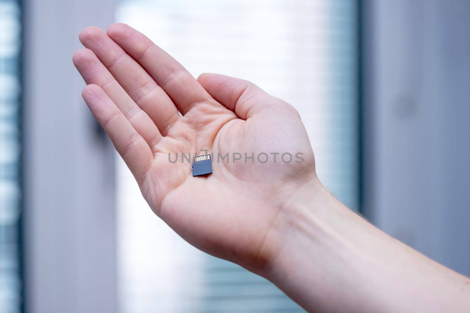 Young man is holding a tiny memory card in his hand, text space
