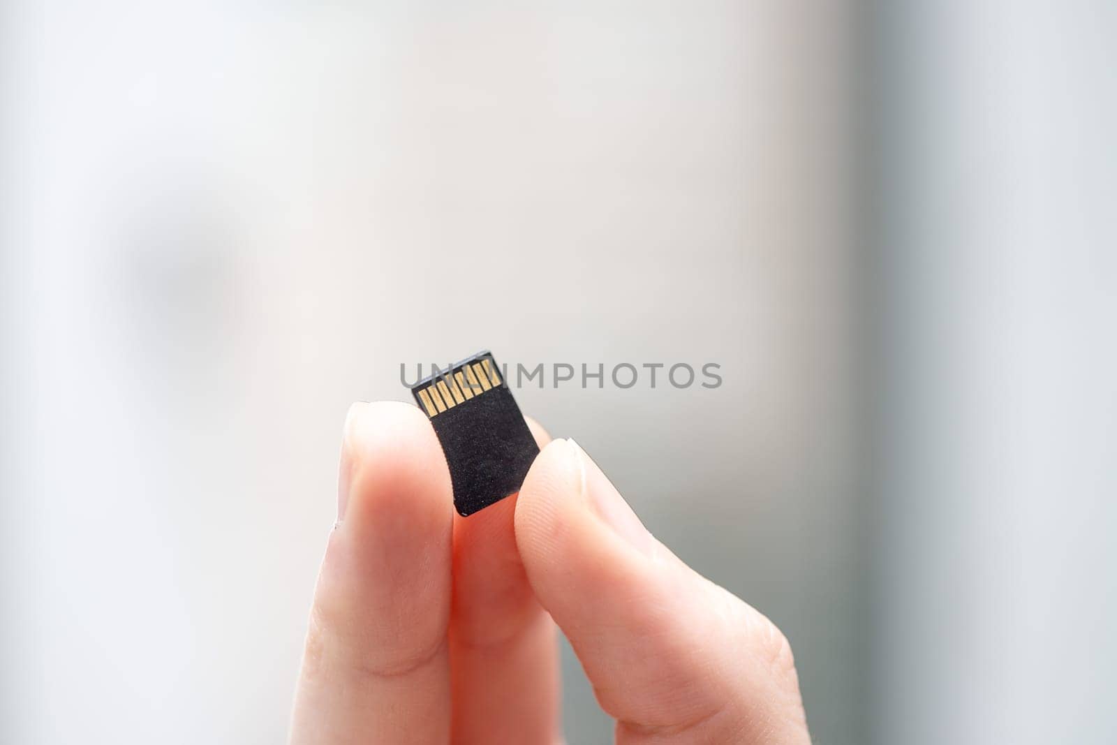 Young man is holding a tiny memory card in his hand, text space