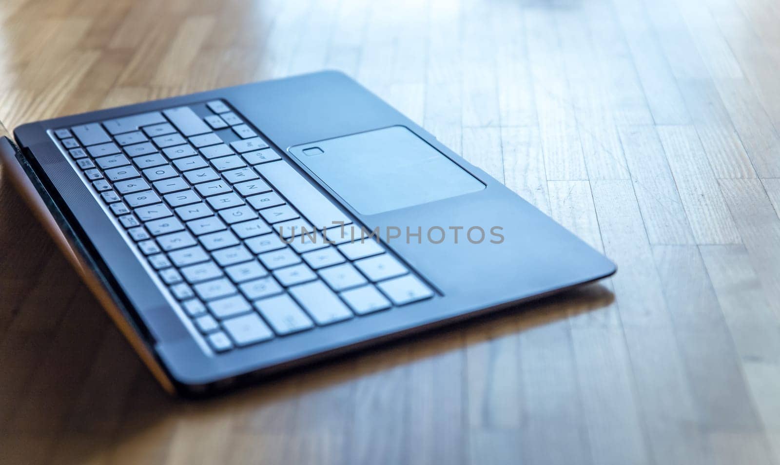 Cutout of a modern laptop keyboard on the wooden floor with text space