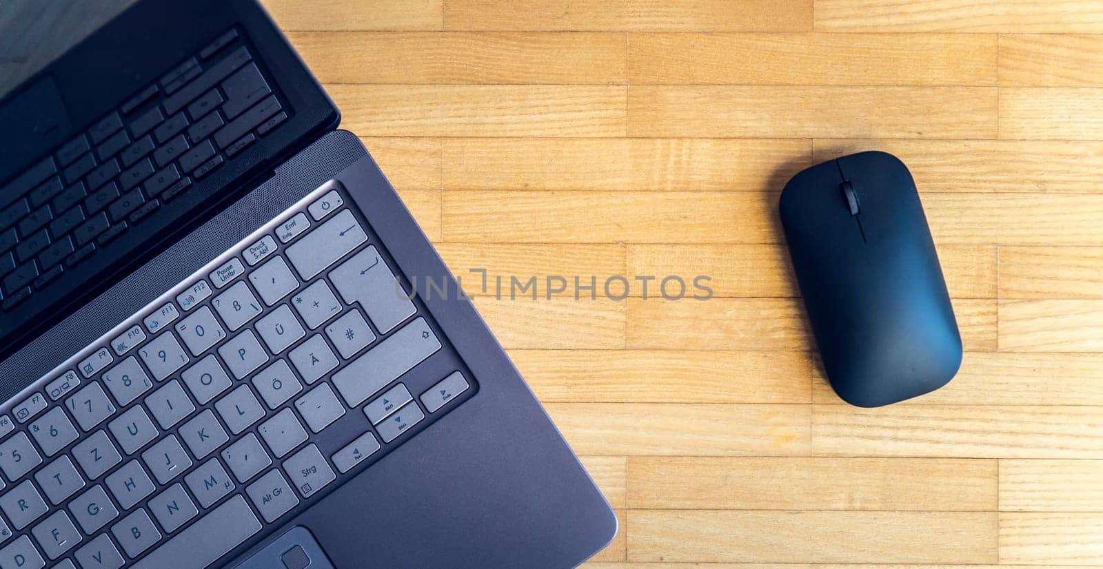 Cutout of a modern laptop keyboard and mouse on the wooden floor with text space