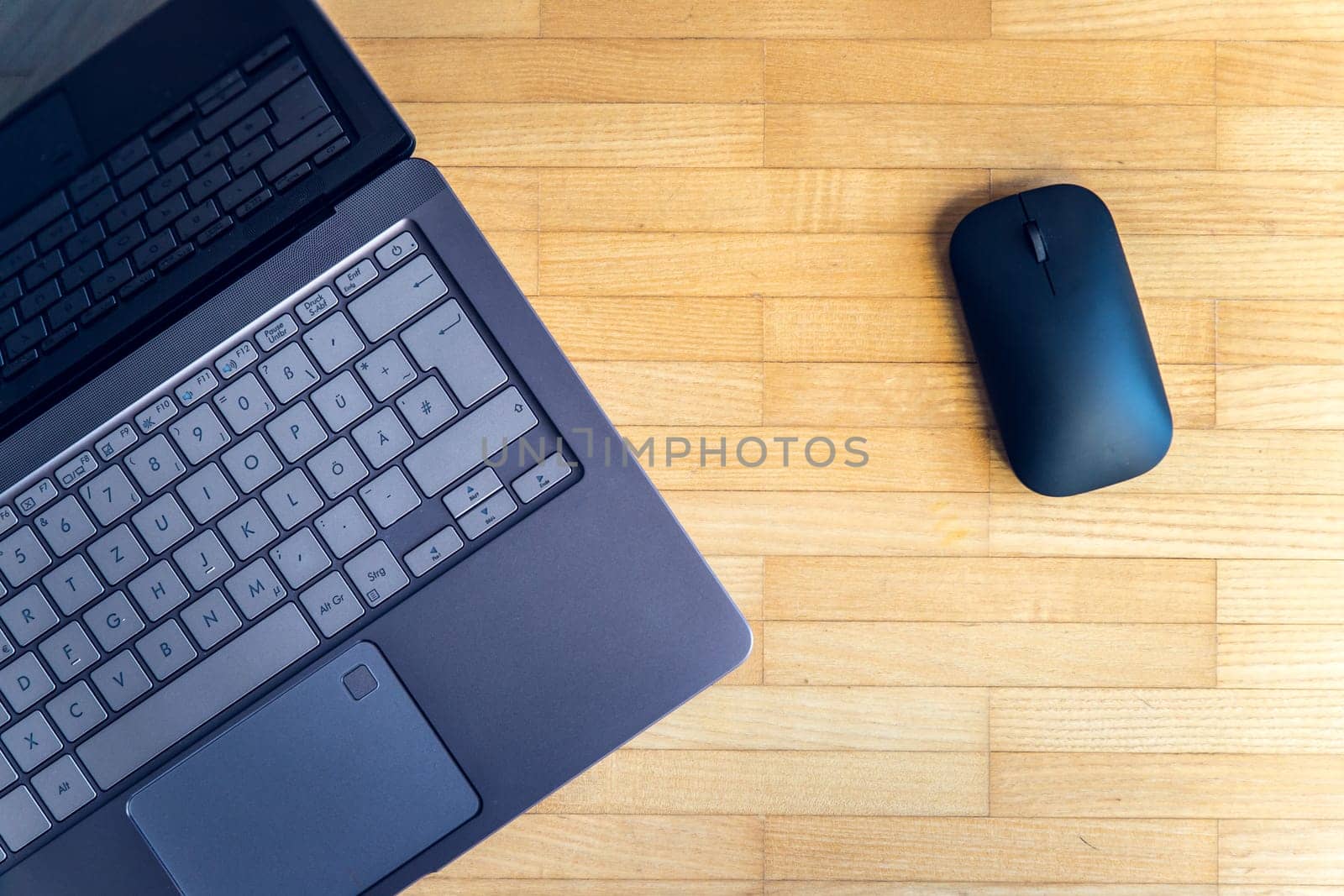 Cutout of a modern laptop keyboard and mouse on the wooden floor with text space