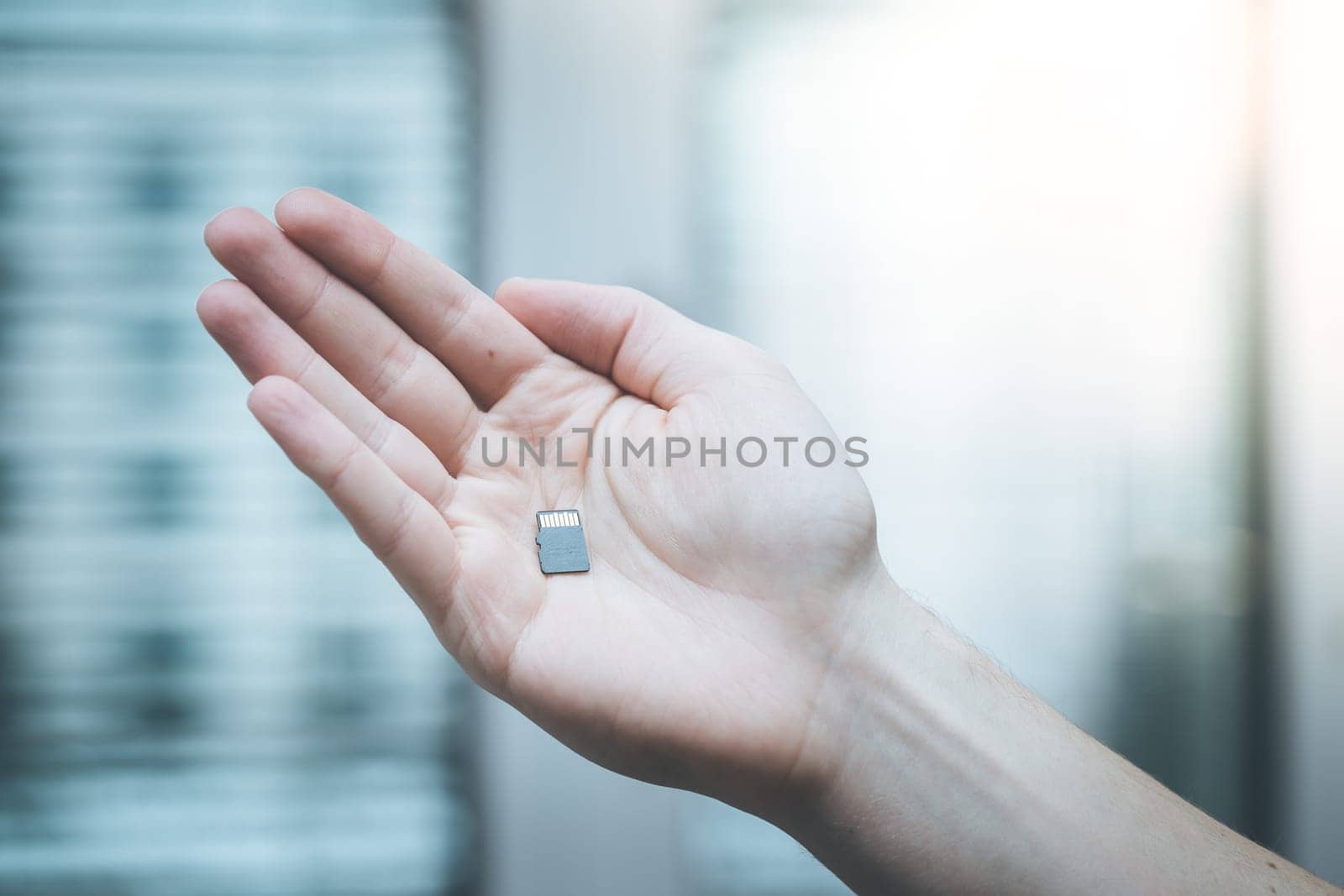 Young man is holding a tiny memory card in his hand, text space