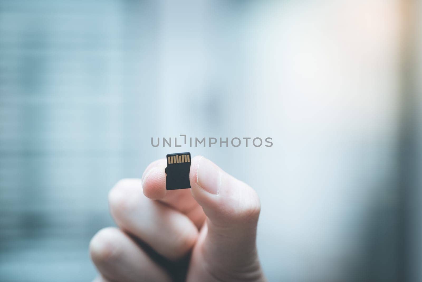 Young man is holding a tiny memory card in his hand, text space