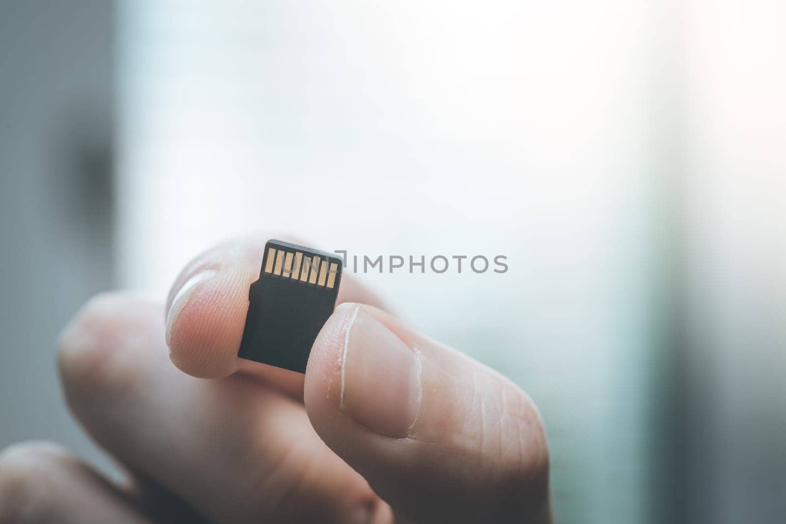 Young man is holding a tiny memory card in his hand, text space