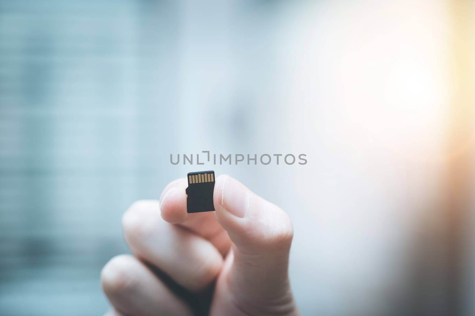 Young man is holding a tiny memory card in his hand, text space