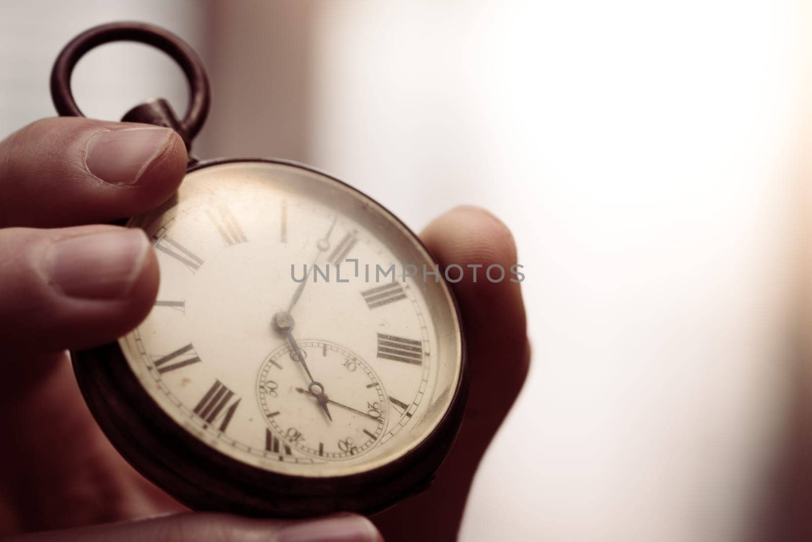 Time goes by: Man is holding a vintage watch in his hand, business context, copy space