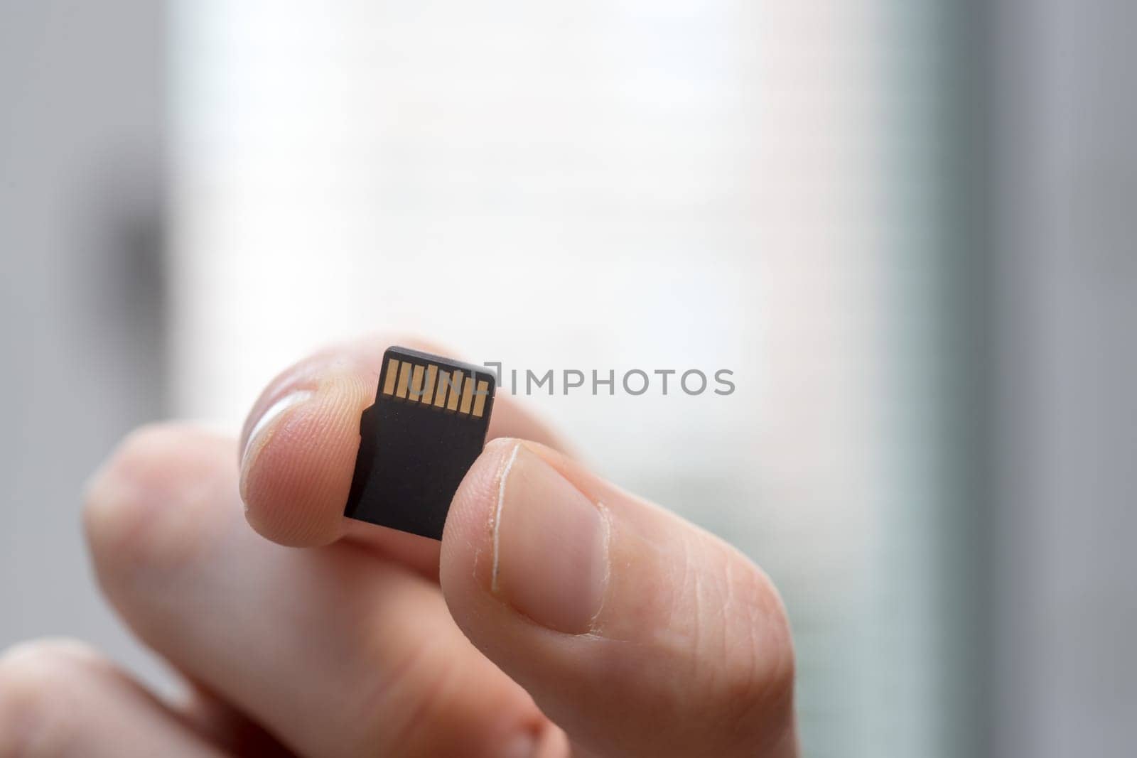 Young man is holding a tiny memory card in his hand, text space