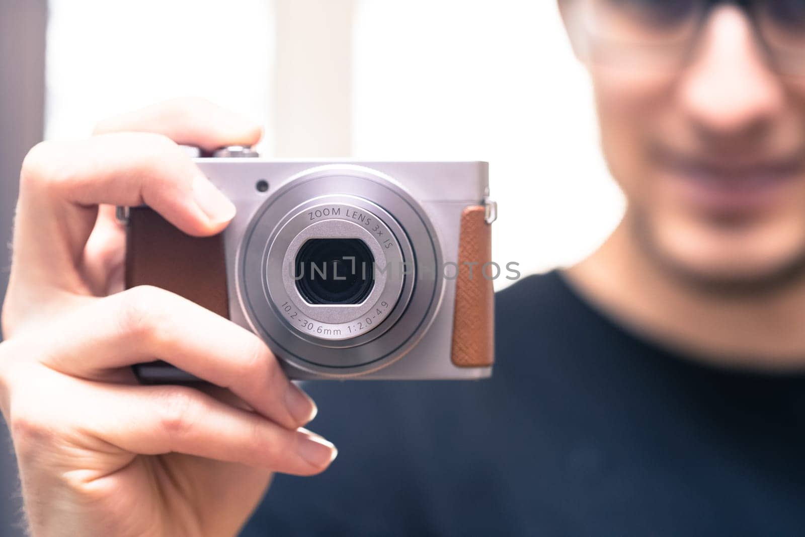 Young man with vintage camera smiles and takes a photo