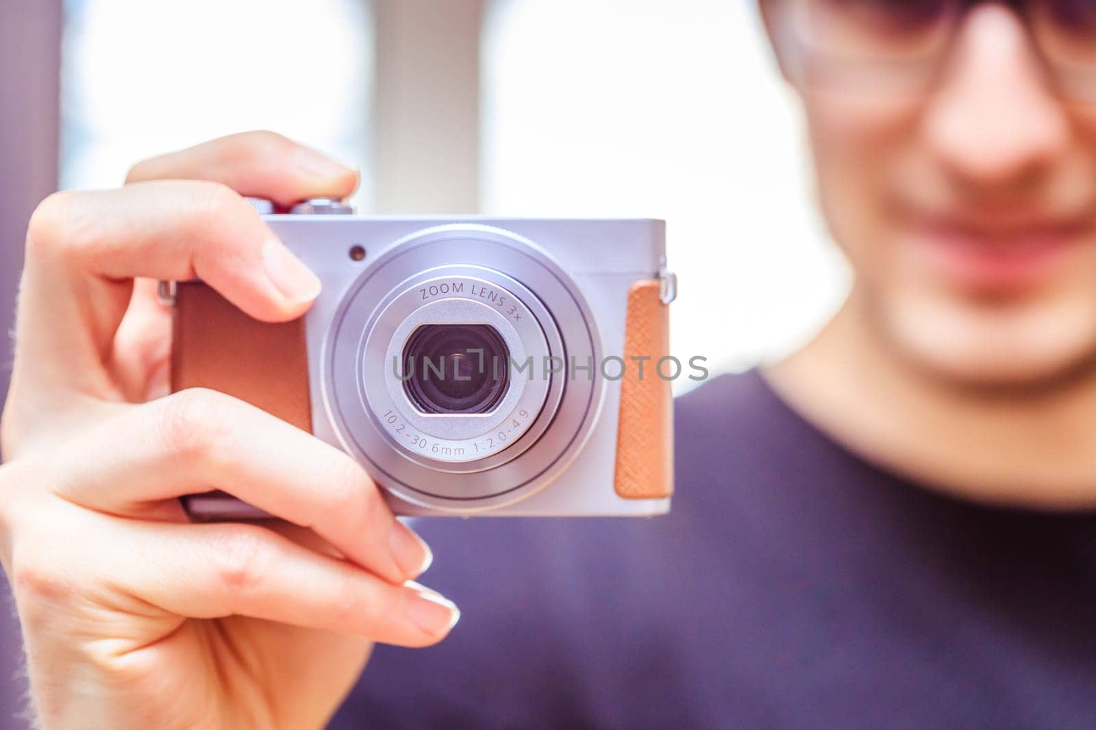 Young man with vintage camera smiles and takes a photo