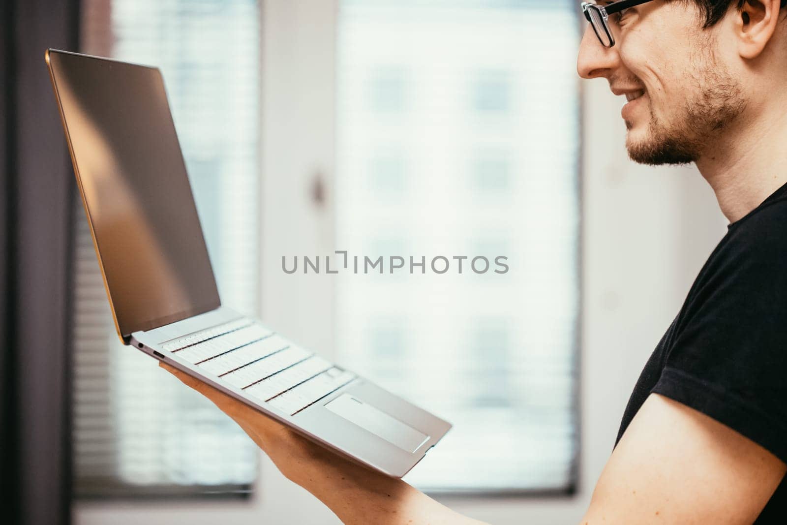 Young freelancer in black shirts holds up a very thin, elegant Ultrabook