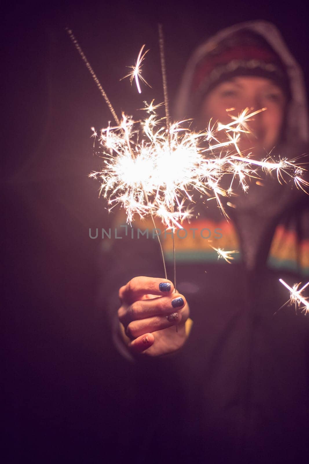 Smiling girl is holding a sparkler in her hand, new year, outdoors