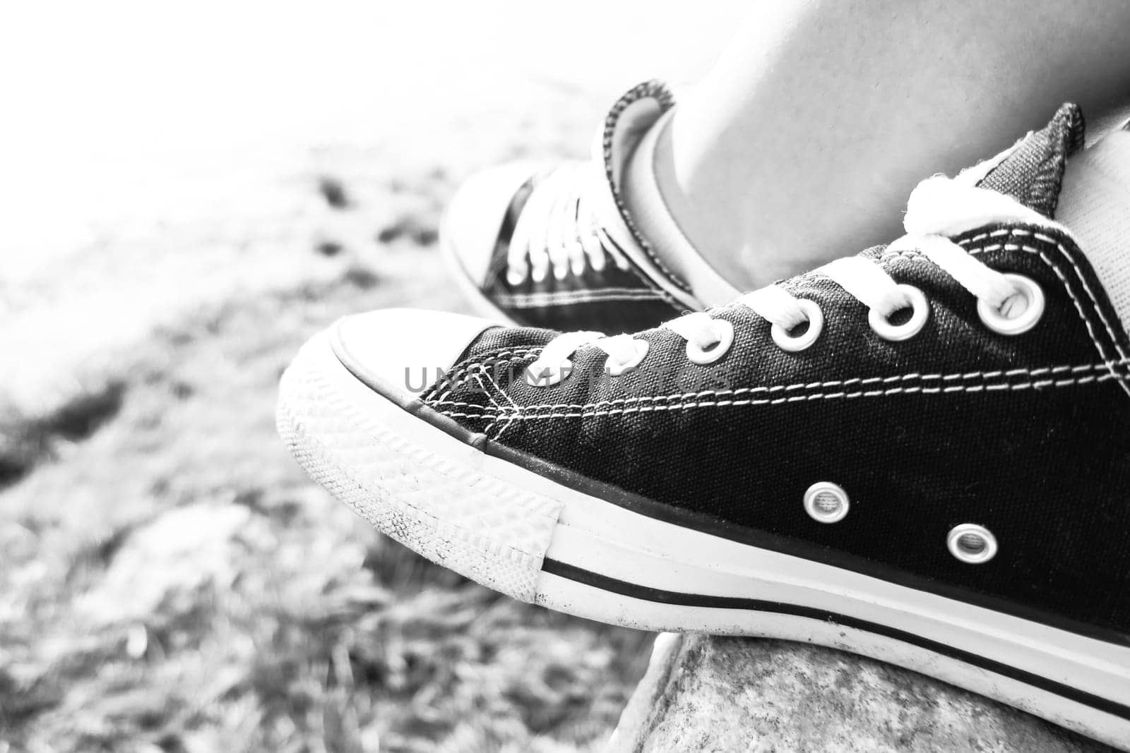 Black sneakers and green grass in the summer: free time for teenager