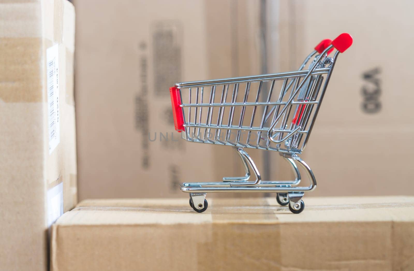 Online-Shopping and parcel service concept: Miniature shopping cart and cardboard boxes