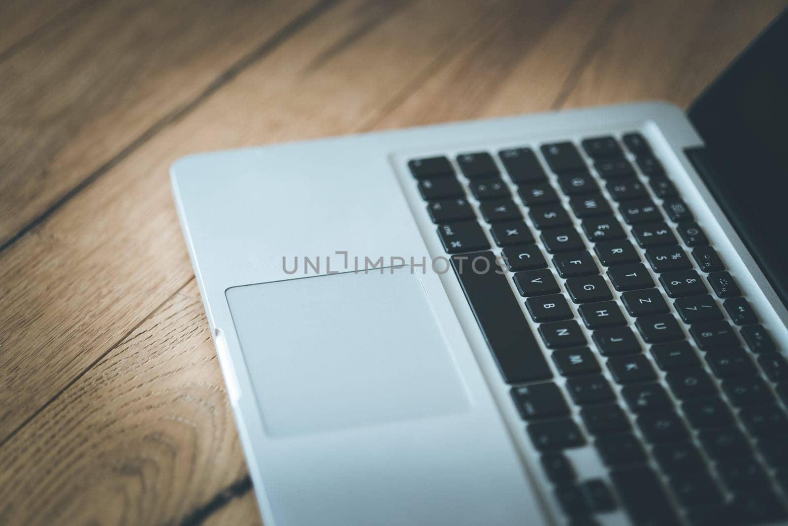 Close up of a laptop keyboard on a rustic wooden desk