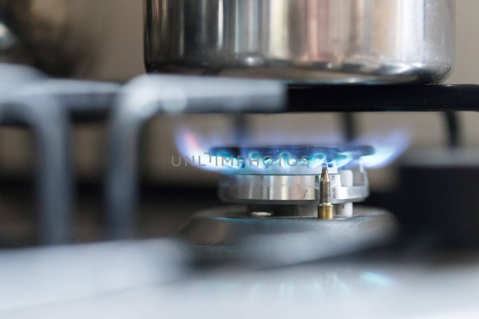 Close up of a blue gas flame, cooking a water pot in kitchen