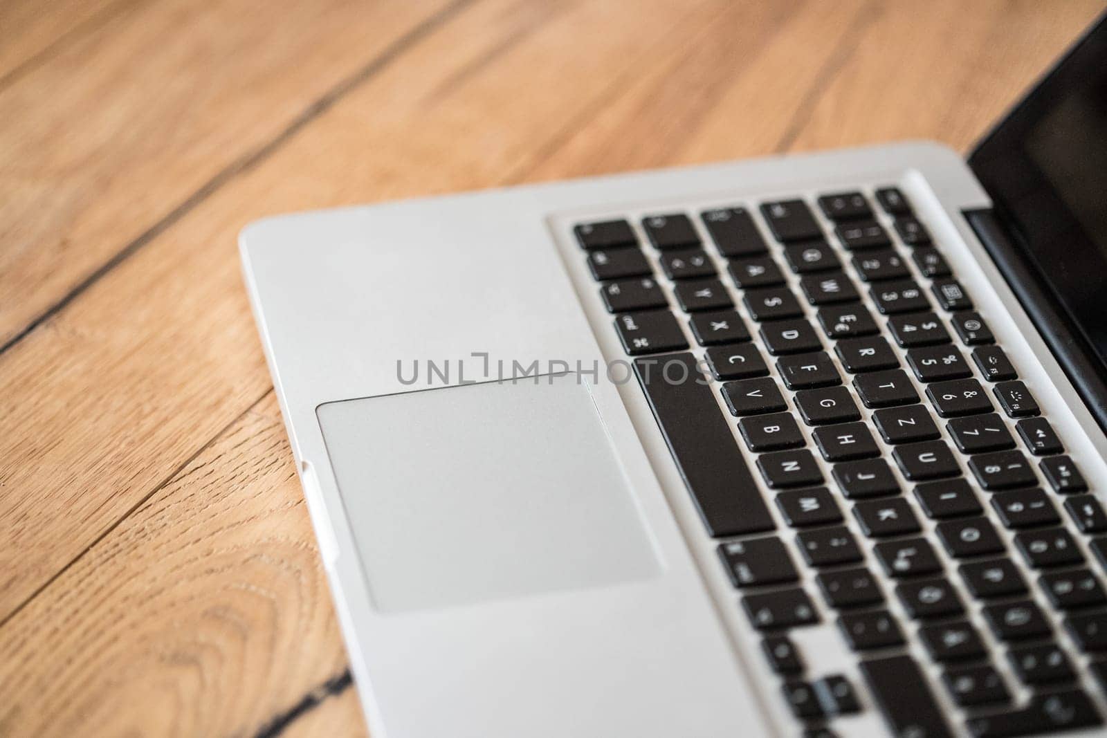 Close up of a laptop keyboard on a rustic wooden desk
