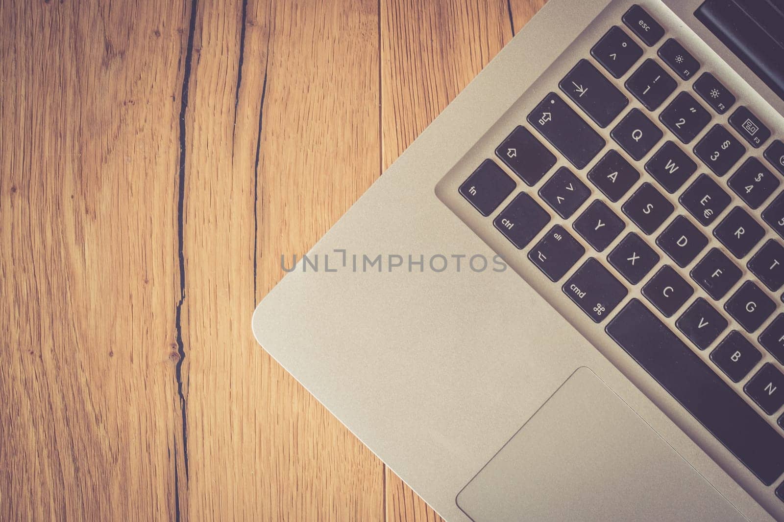 Close up of a laptop keyboard on a rustic wooden desk