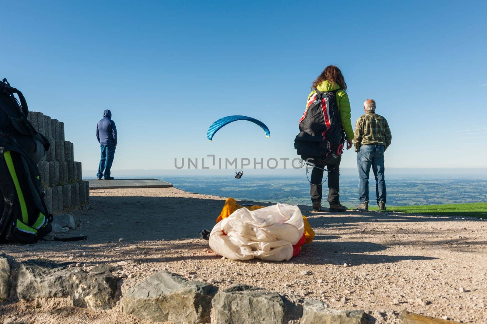 Close-up view of the take-off point for paragliders on the Tegelberg in Bavaria with planes that have just started and people looking behind with a blue sky in summer.