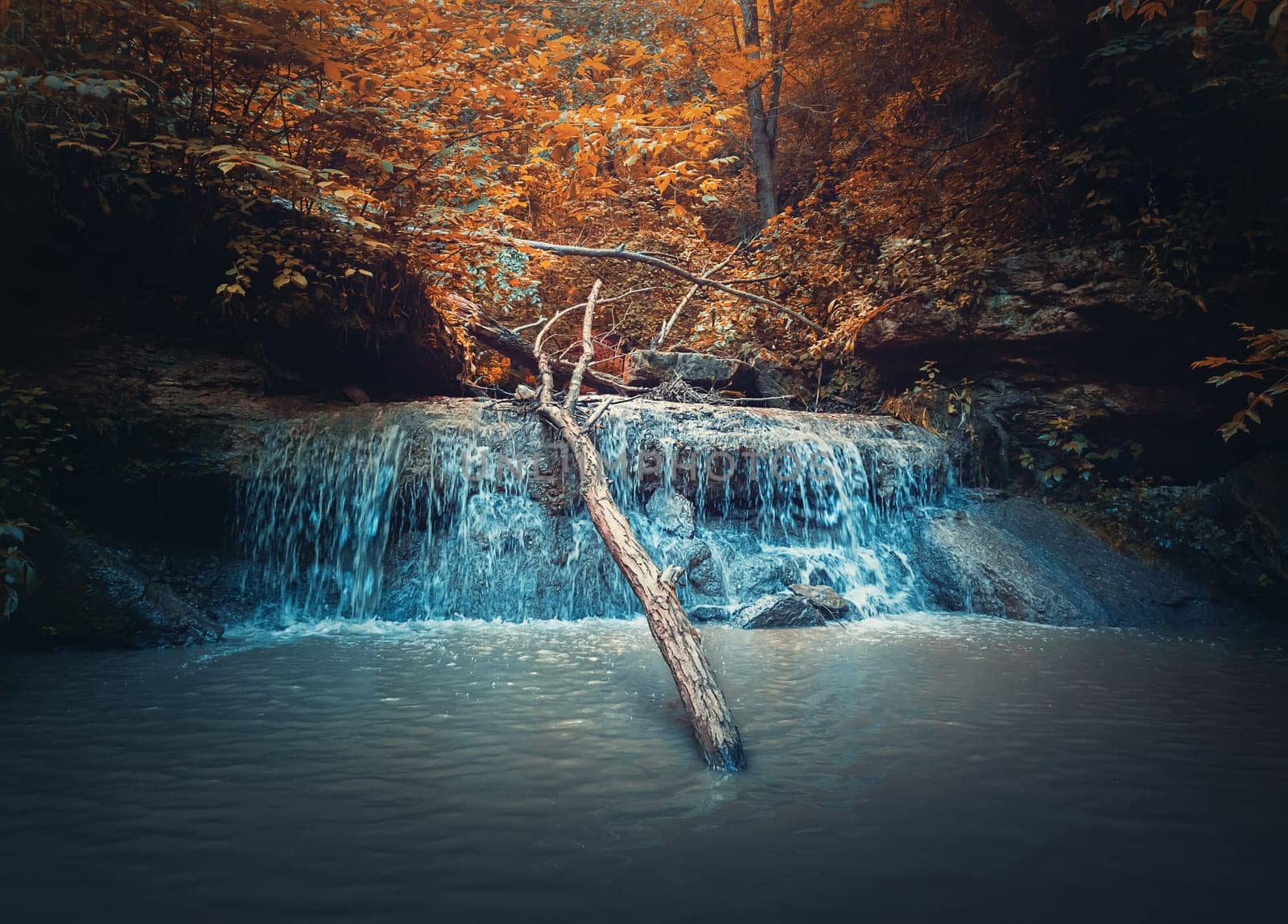 Small creek waterfall with water falling through the autumn woods. Fast stream flowing down from the spring in the forest, through the hills. Saharna cascade called Gypsy Hole, Moldova
