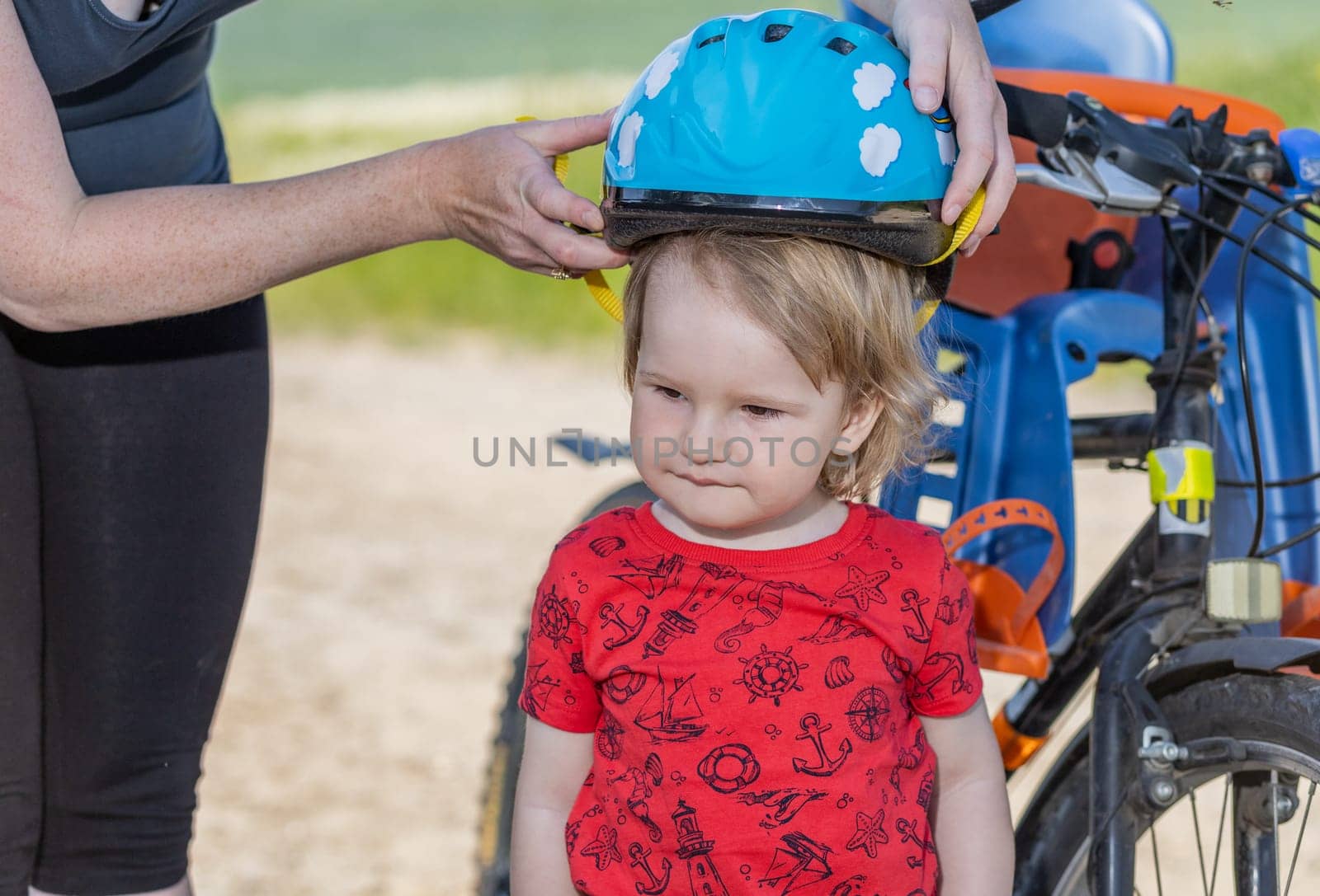 Mother puts on the  head of her little son safety bicycle helmet