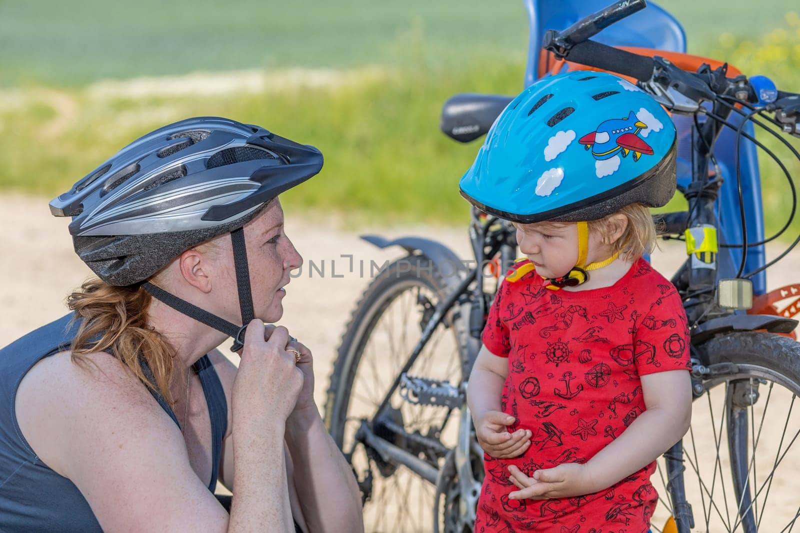Cycling safety concept. Mother with her son using safety helmet. All potential trademarks are removed.
