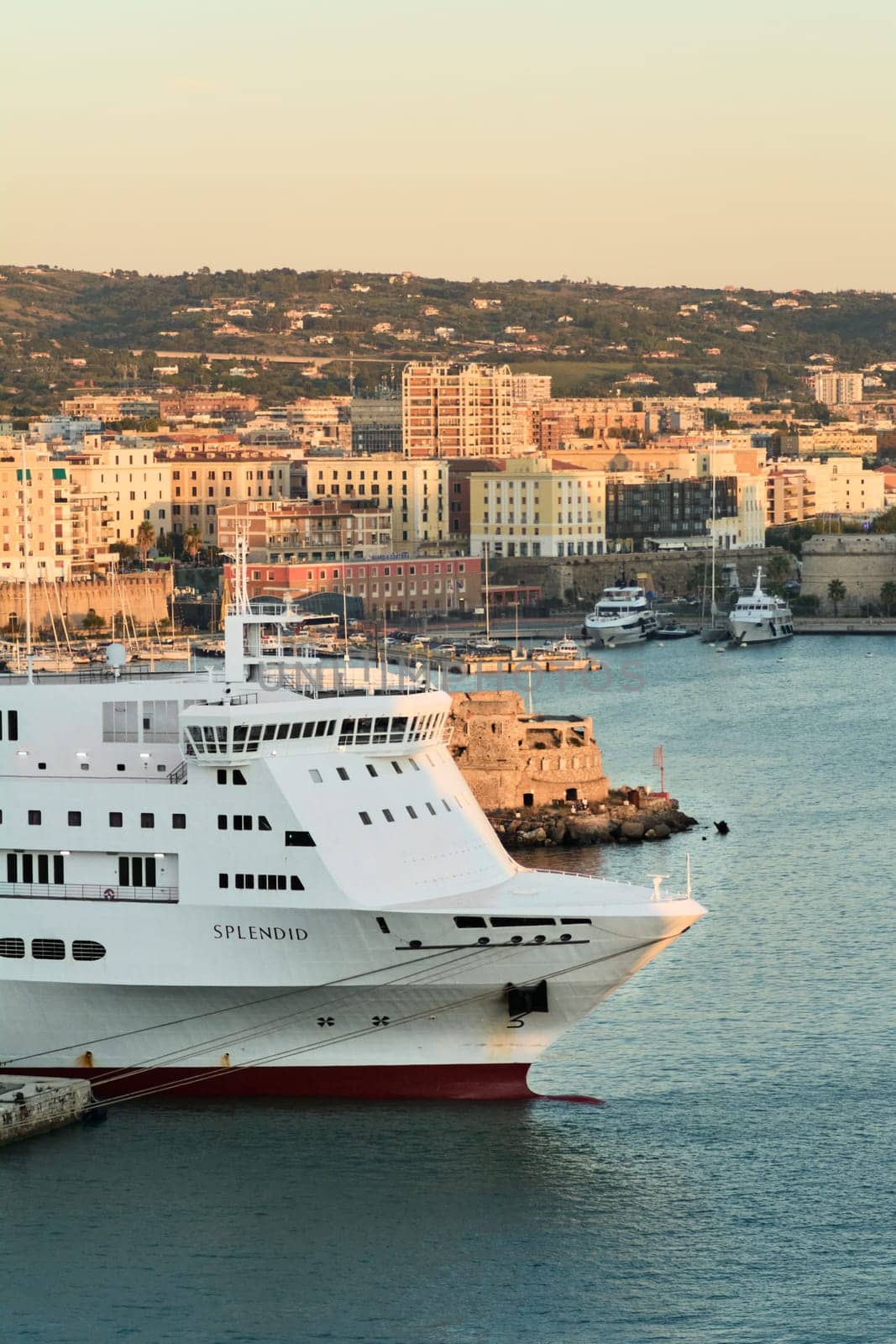 Civitavecchia. Italy - February 07, 2025: The ferry Splendid moored in Civitavecchia s harbor near an ancient stone fortress. A scene of modern naval transport against a historic coastal landscape. Concept: travel, tourism, and naval industry