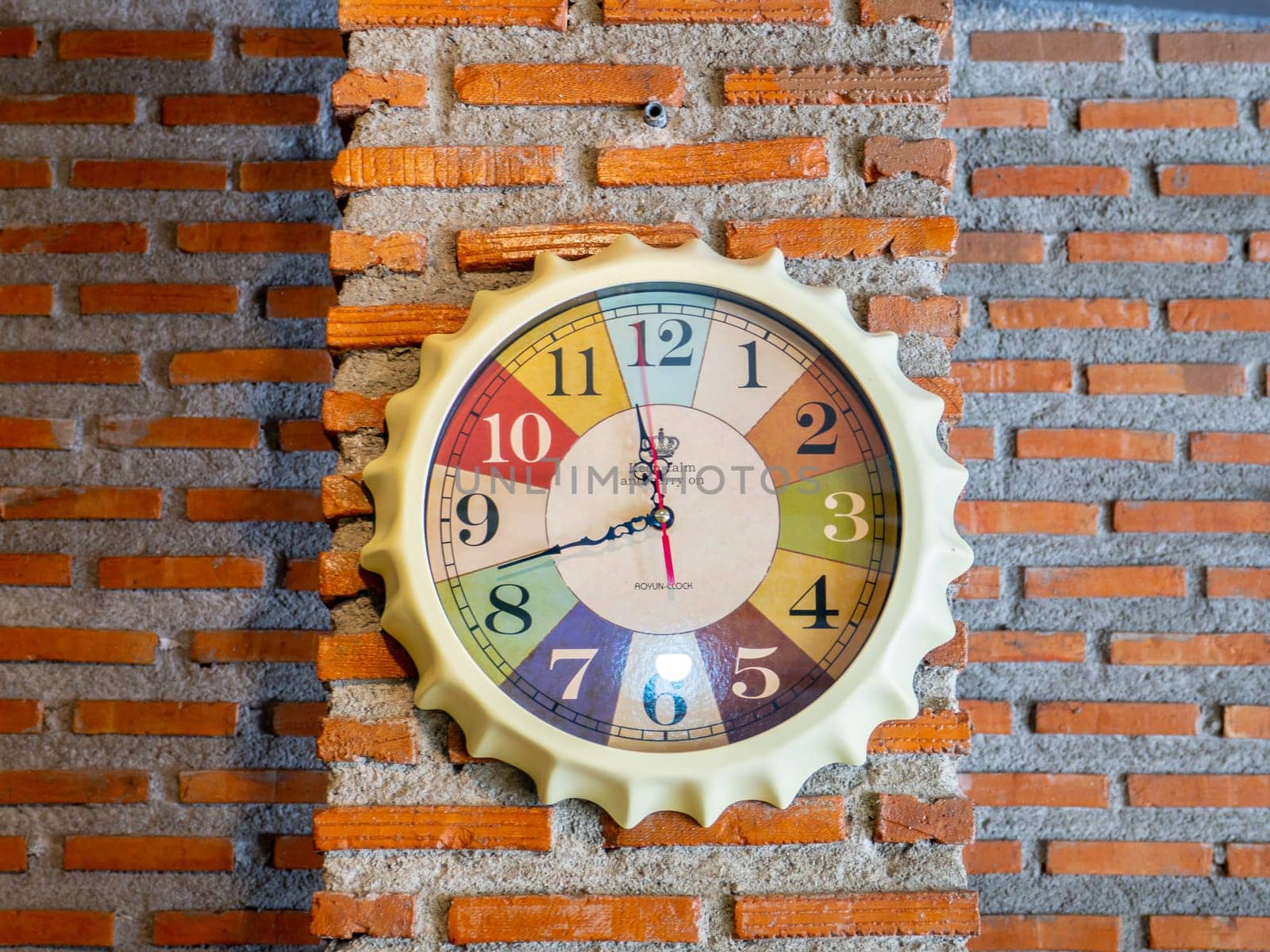 Stylish analog clock hanging on brick wall. Space for text