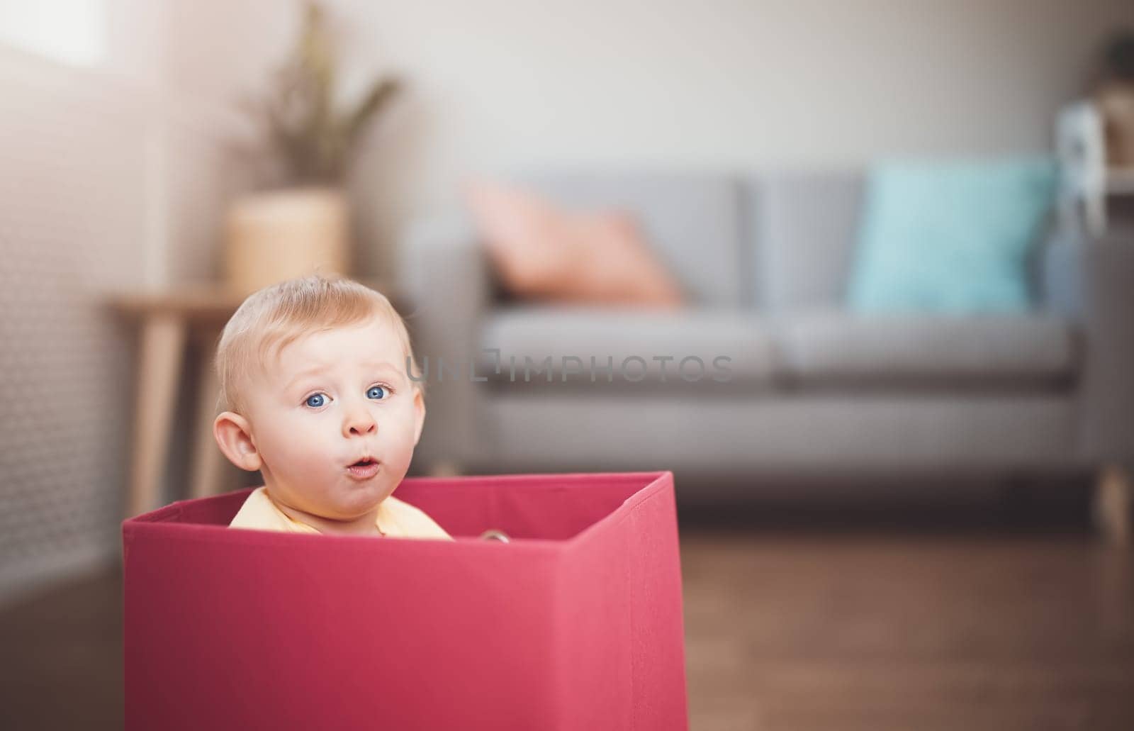 Cute boy sitting in the red box. Surprised child. Concept of the family and mother's love.