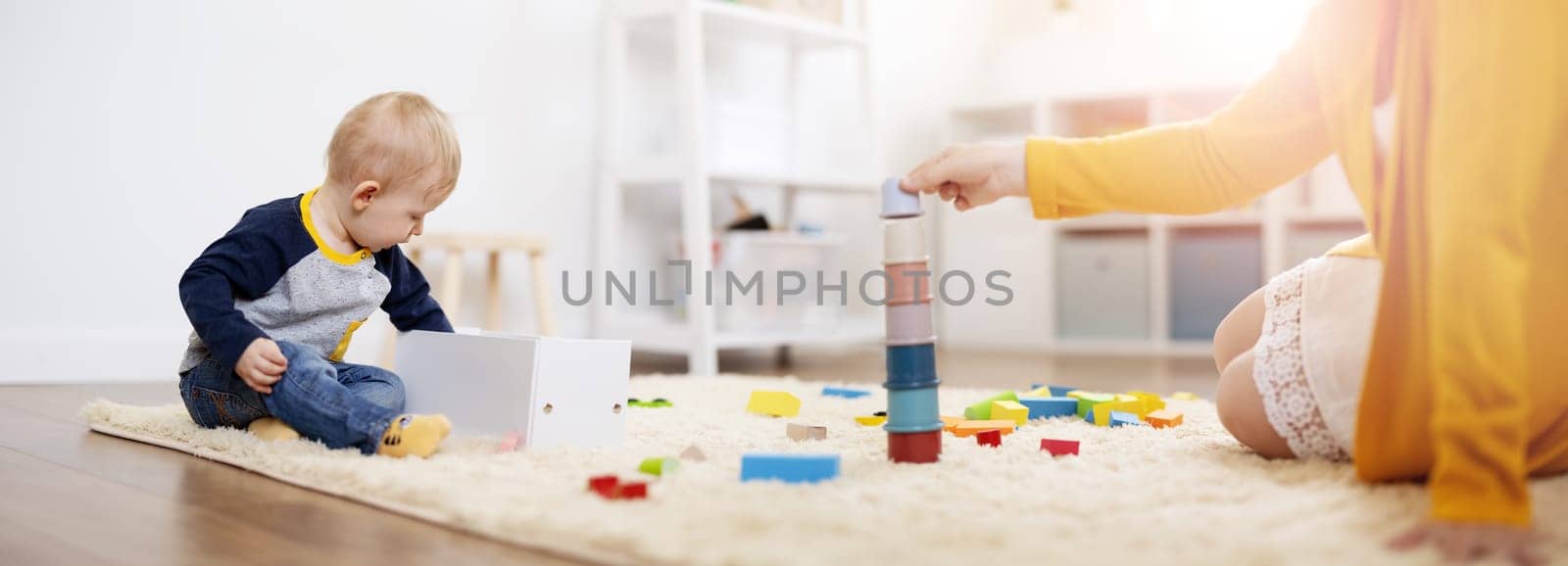 Mother playing with her cute son on the floor. Concept of the family relationship, mother's love and development of the child through the play.