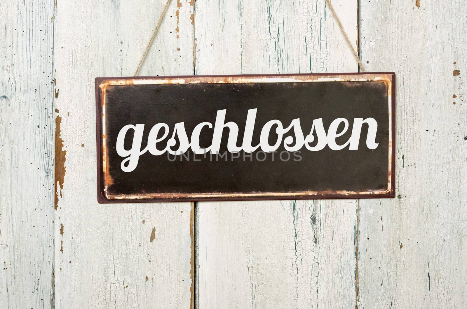 Old tin sign in front of white wooden wall - closed