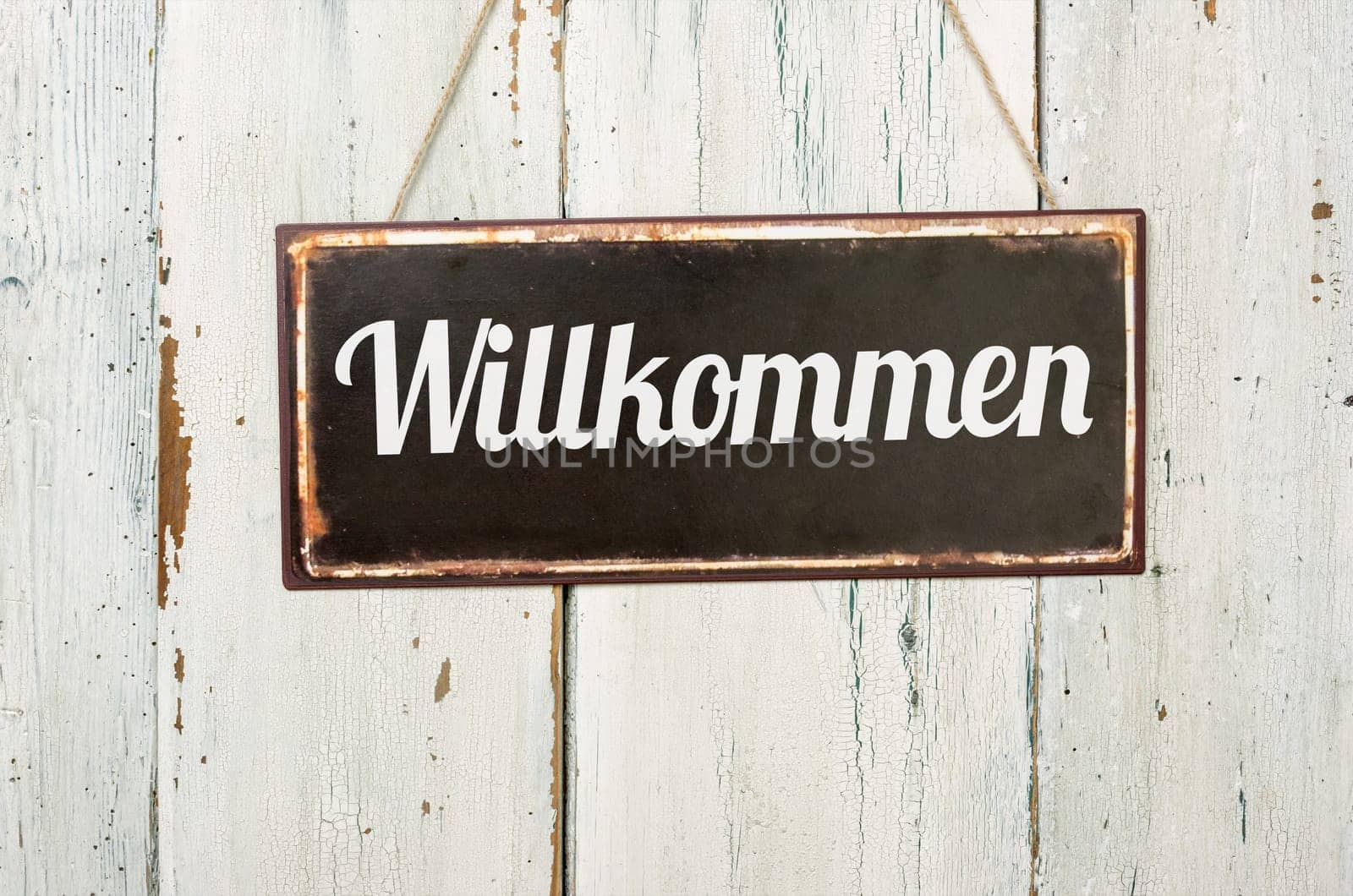 Old tin sign in front of white wooden wall - Welcome
