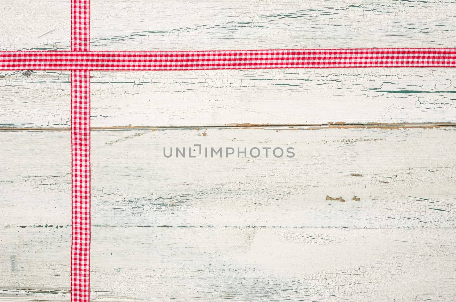 Red plaid gift ribbons in front of white wooden boards