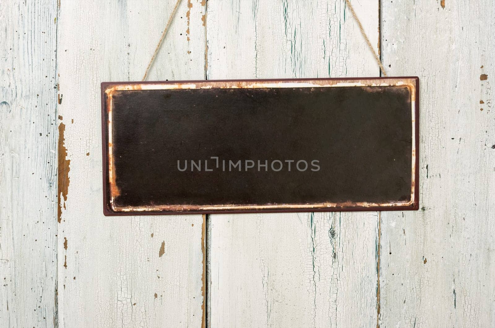 Empty tin sign in front of white wooden wall