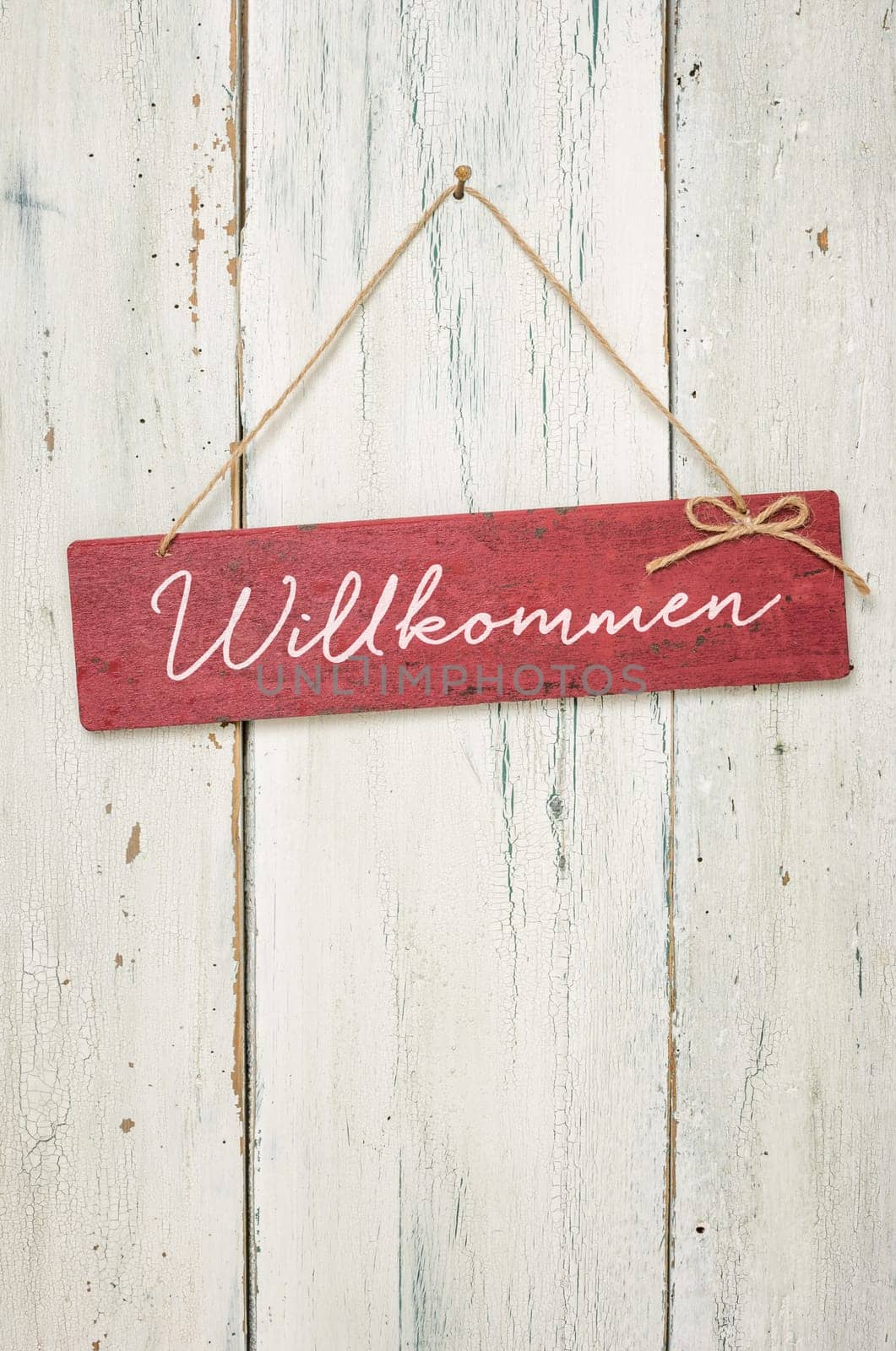 Red wooden sign in front of white wooden wall - Welcome