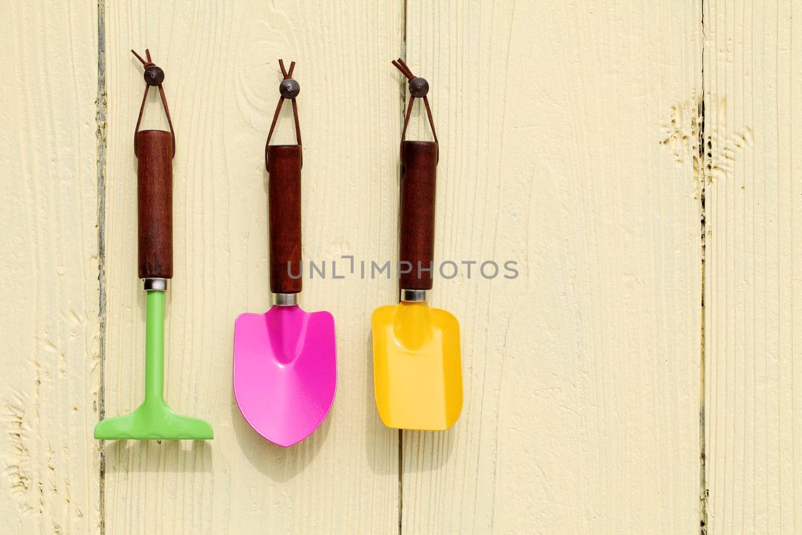 garden tools hang on wooden wall