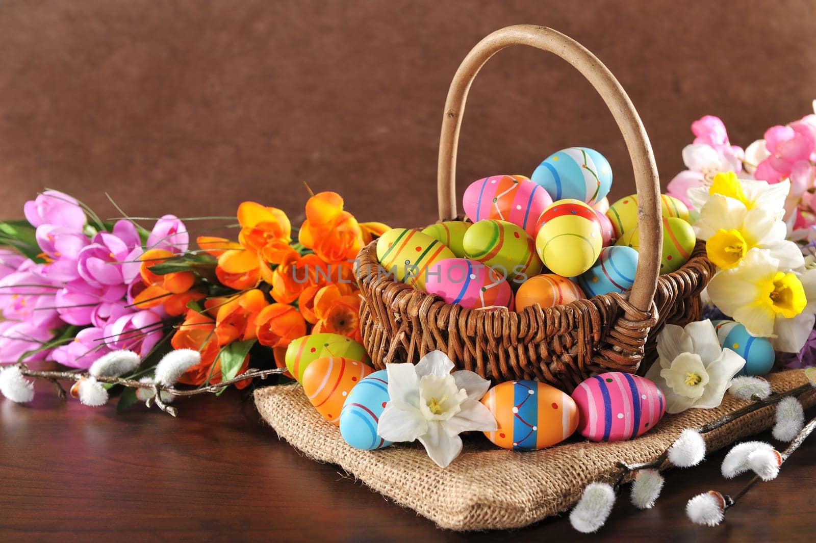 Easter nest with many painted Easter eggs,daffodils and palm kittens