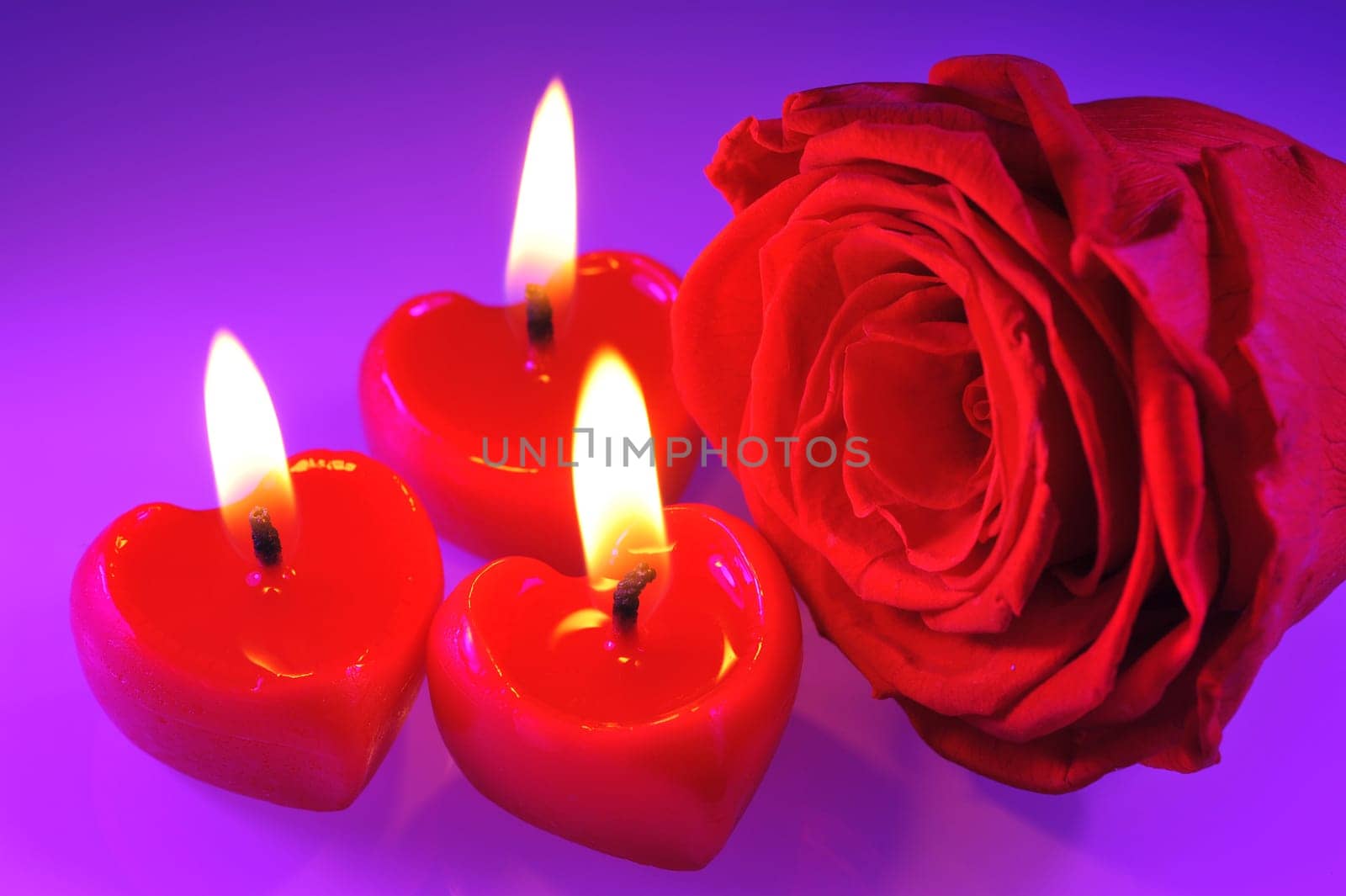 Three bright red candles in heart shape with red rose