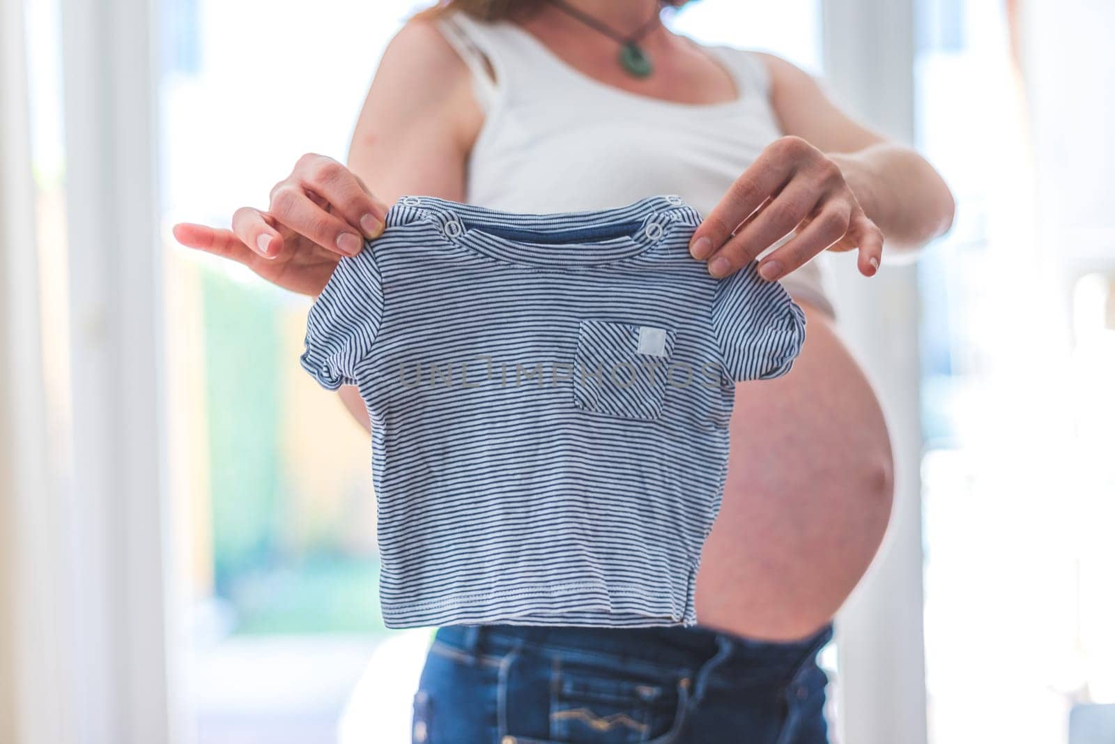 Happy Caucasian pregnant mother holding little baby shirt