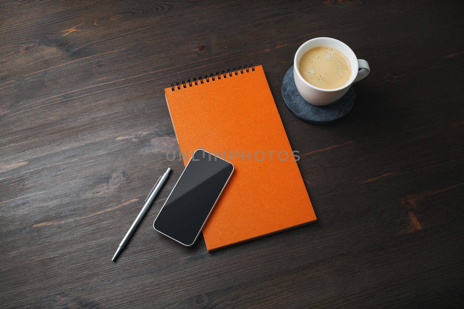 Smartphone, blank notepad, coffee cup and pen on wooden background. Template for placing your design.