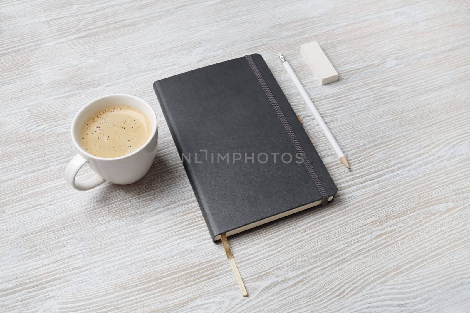Photo of blank notepad, coffee cup, pencil and eraser on light wood table background. Branding identity template.