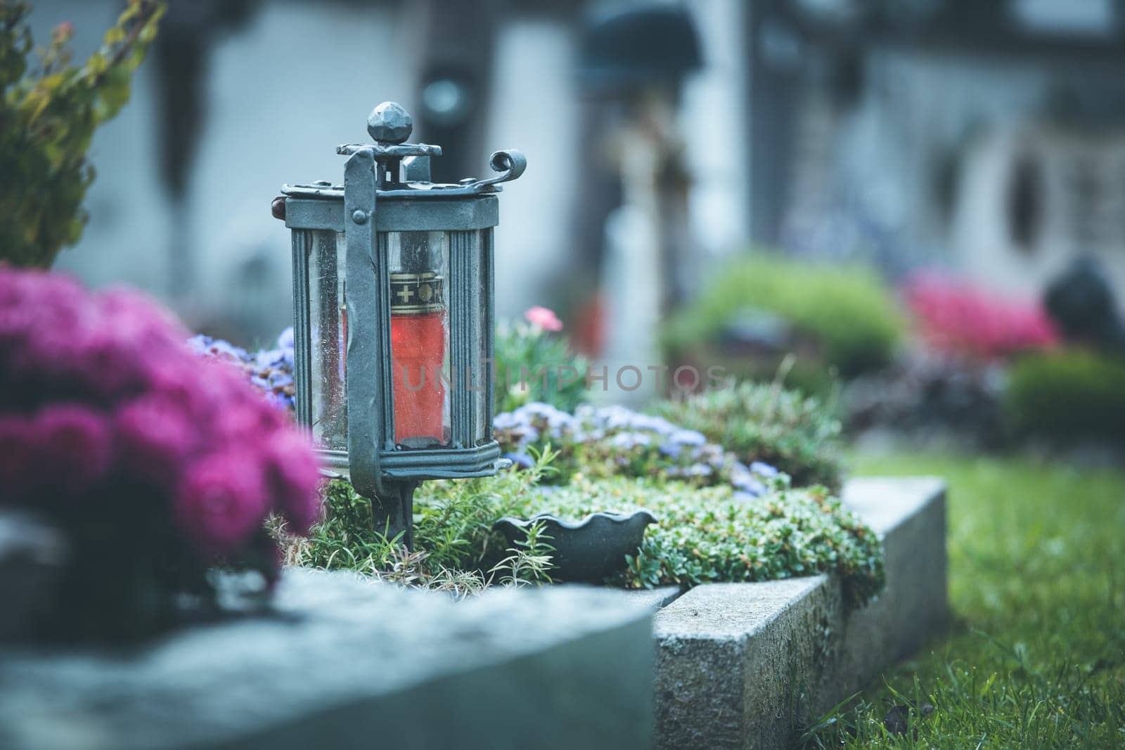 Candle in an iron lantern on a grave at a cemetery