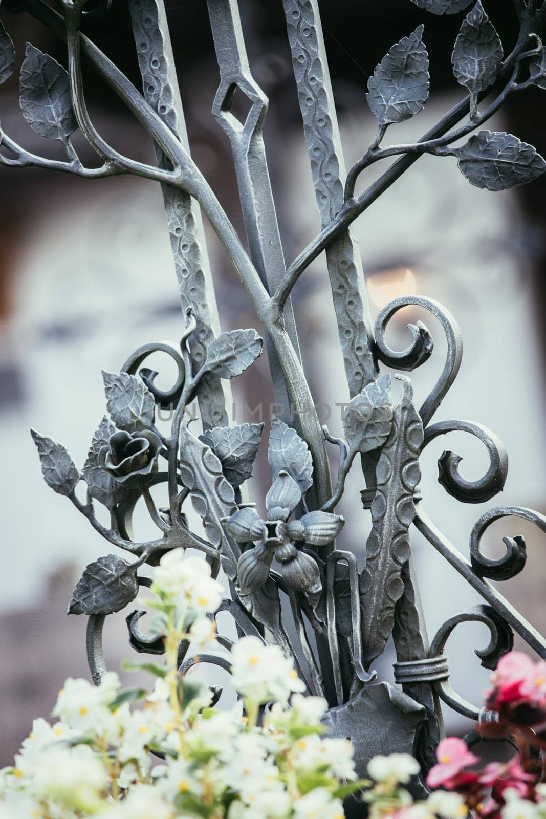 Iron sculpture on a grave at a cemetery, tombstone and flowers