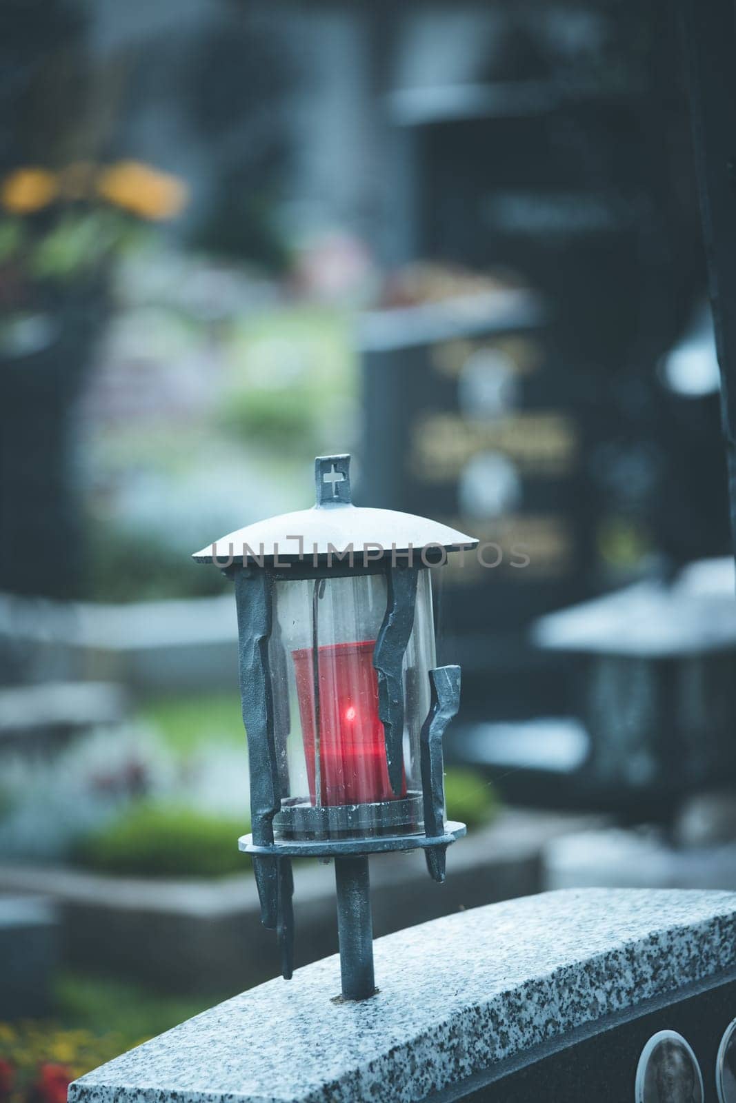 Candle in an iron lantern on a grave at a cemetery