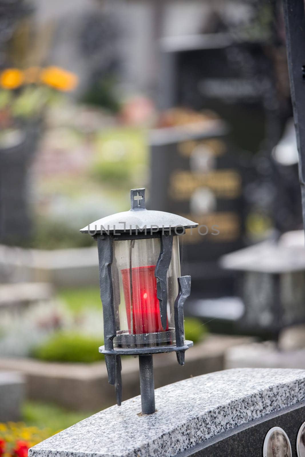 Candle in an iron lantern on a grave at a cemetery