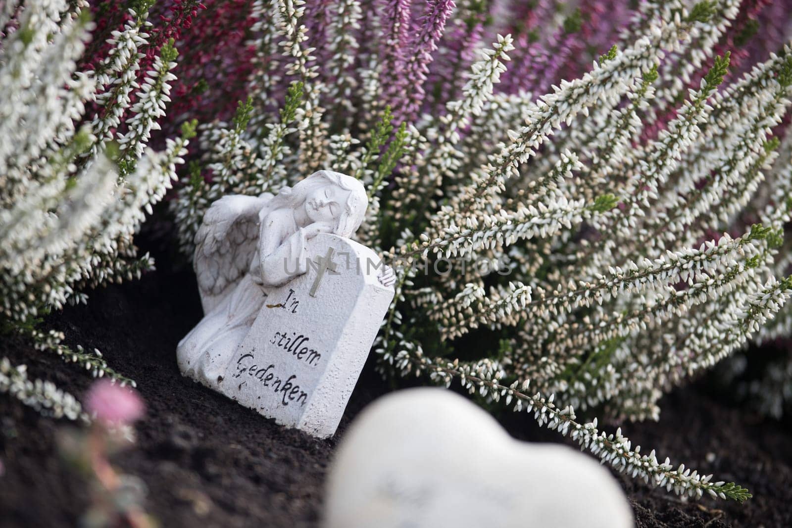 White angel on a grave at a cemetery, flowers