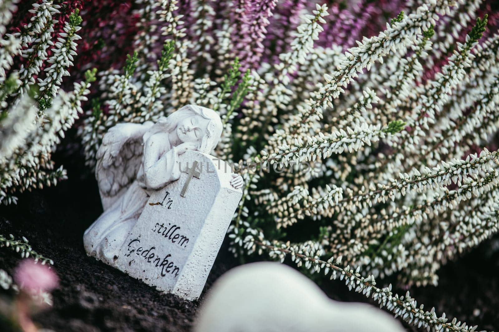 White angel on a grave at a cemetery, flowers