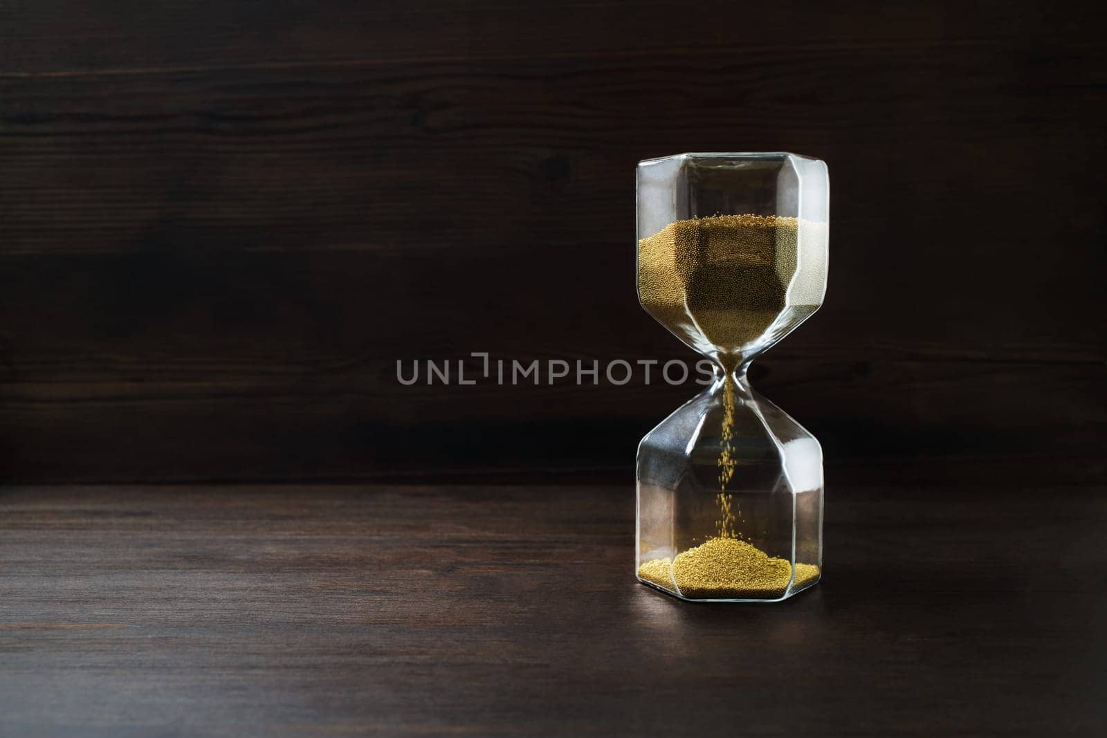 Hourglass on dark wooden background. Time concept.